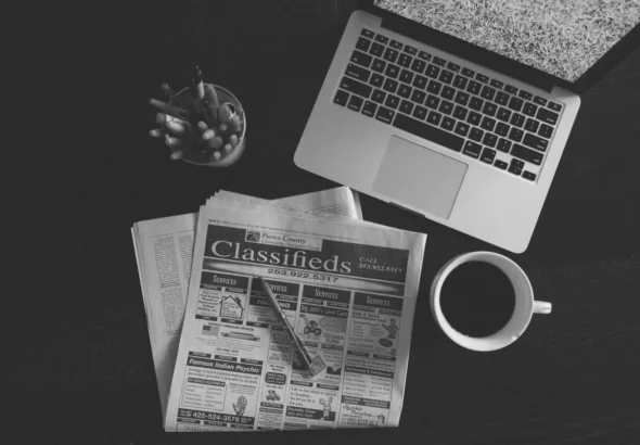 Publieditorial em Salvador: redação editorial com laptop, jornal e café em mesa de trabalho