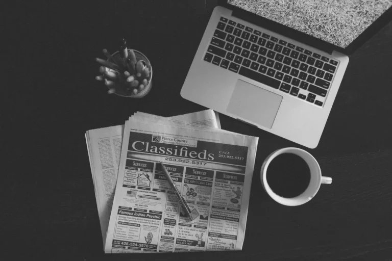 Publieditorial em Salvador: redação editorial com laptop, jornal e café em mesa de trabalho